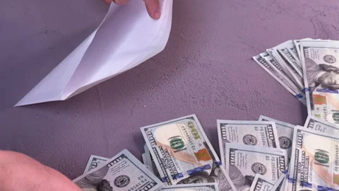 A man sitting at a table counts dollars and puts them in an envelope Stock Footage 304755639