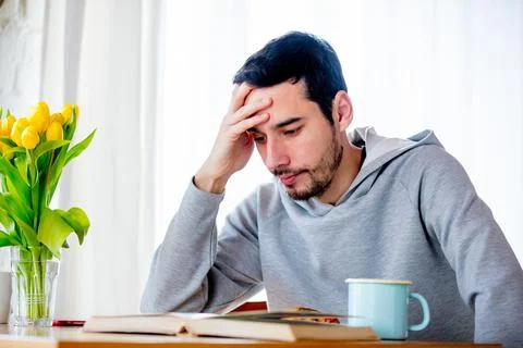 Man sitting at table with cup of coffee or tea and book. Stock Photos