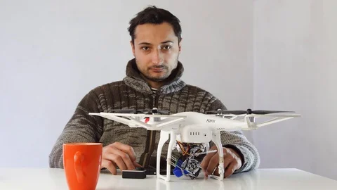 The man is sitting at the table with a drone and an action camera 스톡 동영상 87569946