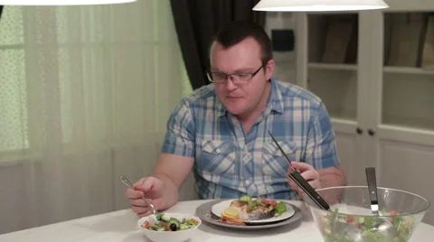 Man sitting at a table eating salad Stock Footage 58653681