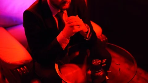 Man sitting at the table with five bullet cases on it. Shooting in bright red Stock Footage 101546626