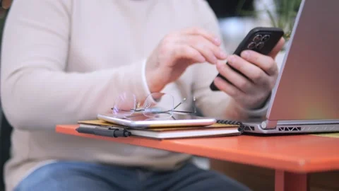 Man is sitting at a table with a laptop and a cell phone Stock Footage 307005608