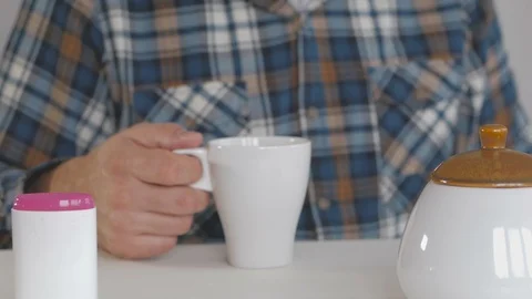 A man sitting at the table makes a choice between sugar and sweetener Stock Footage 100975596