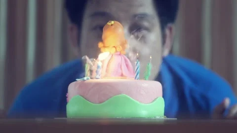 A Man is sitting at a table with a pink cake with a little girl on top of it Stock Footage 319393024