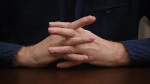 Man sitting table puts his hands in lock. gesture man who is in waiting. closeup Stock Footage 297814882