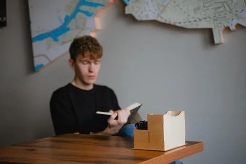 A man sitting at a table reading a book Stock Photos