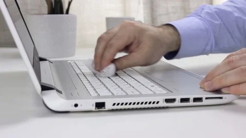 A man sitting at a table rubs a laptop keyboard. Cleaning and disinfection, Stock Footage 128103741