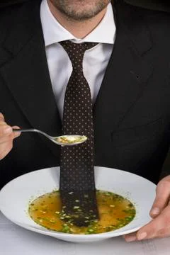 Man sitting at table with tie floating in bowl of soup Stock Photos