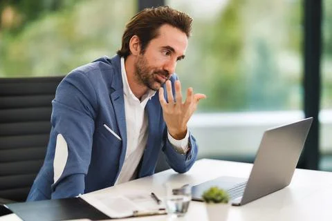 A man sitting at a table using a laptop Stock Photos