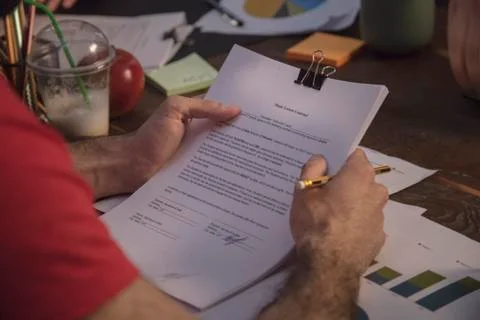 Man sitting at table with various documents and holding contract Stock Photos