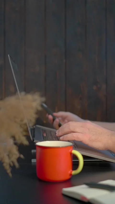 Man sitting at table working on computer, picking up and looking at smartphone Stock Footage 170784937