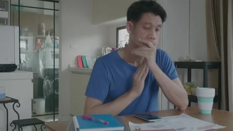 A man is sitting at a table working with Financial data a cell phone and a stack Stock Footage 314273484