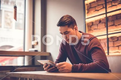 The man sitting with a tablet at the restaurant table Stock Photos