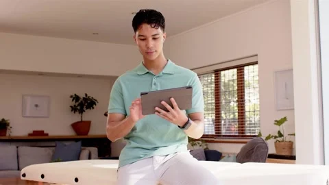 Man sitting tapping tablet in home teal frames popping, sparks on hands marking Stock Footage 333837688