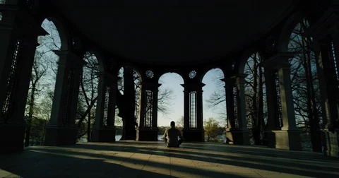 A man sitting in temple and meditating at sunrise Stock Footage 77543769