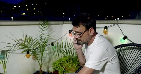 A man sitting on a terrace talking on his mobile phone Stockbeeldmateriaal 336310400