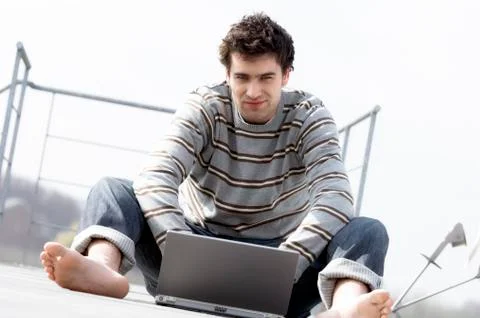 Man sitting on a terrace using laptop computer Stock Photos