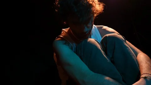 Man sitting is thinking to himself. contemplation. studio shot in black backgrou Stock Footage 126861866