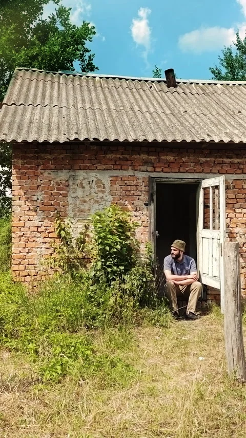 Man Sitting on Threshold of Old Rustic Brick House Stock Footage 339620207