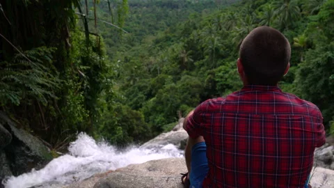 A man is sitting on the top of a waterfall Stock Footage 91793126