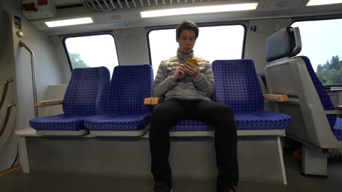 A man is sitting on a train with a cell phone in his hand Stock Footage 314611736