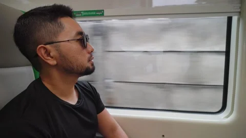 Man Sitting by Train Window Looking Outside During Journey 스톡 동영상 332050951