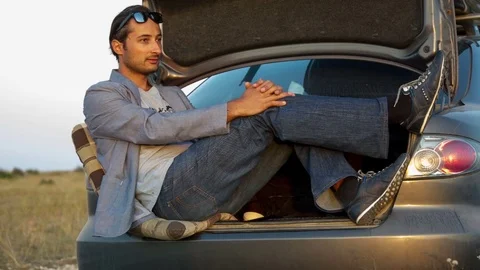 The man is sitting in the trunk of the car Stock Footage 81175796