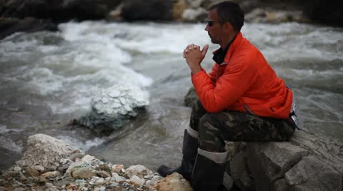 Man sitting on trunk on mountain trail. Mountain stream with stones Video stock 25742276
