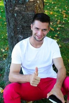 Man sitting under a tree with thumb up Foto stock