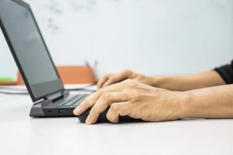 A man sitting using a laptop with hand to hold a mouse 스톡 사진