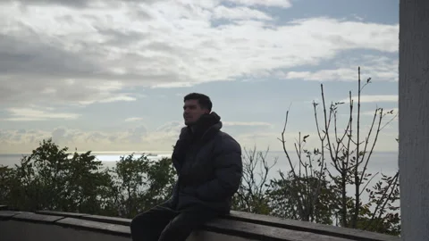 Man Sitting on Viewpoint with Sea View, Looking Away Stock Footage 327136662