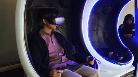 A Man Sitting on Virtual Reality Game Capsule, Floating Market Lembang Stock Footage 130249123