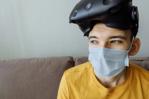 The man is sitting in virtual reality glasses and masks on self-isolation. Stock Photos