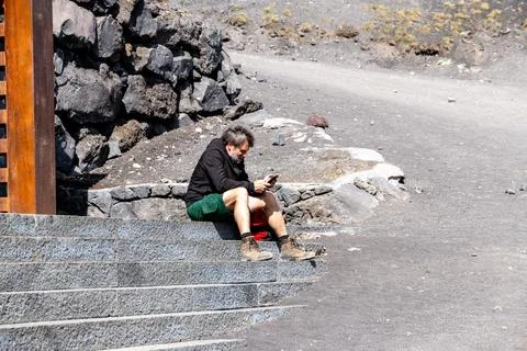 Man sitting on volcanic steps at Mount Etna Foto stock