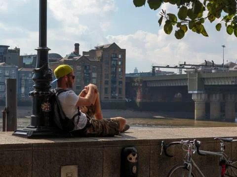 Man sitting on a wall by the River Thames Stock Photos