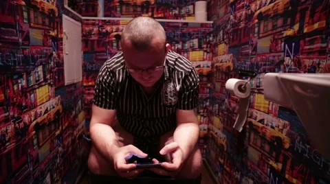 Man sitting in WC and plays on a Smartphone Stock Footage 57862972