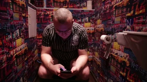 Man sitting WC and using internet in mobile phone Stock Footage 57230469