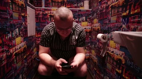 Man sitting in WC and using mobile phone Stock Footage 57233008
