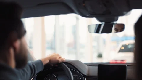 Man sitting at wheel of new car. Young handsome man with beard regulating and Stock Footage 86174601