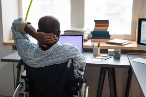 Man sitting on wheelchair working on laptop Stock Photos