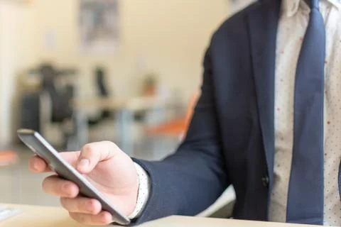 Man sitting while using the mobile smartphone. Confident Entrepreneur working on Stock Photos