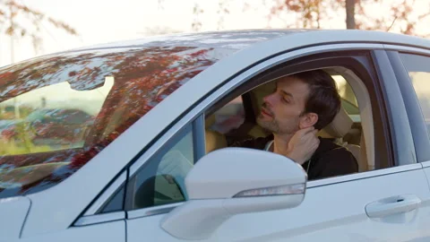 Man sitting in a white car, looking thoughtfully out of the window, with autumn Video stock 315531835