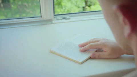 A man sitting by the window reading a book, rear view Stock Footage 191614772