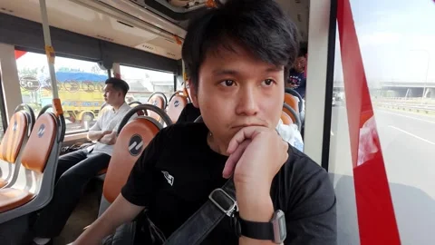 Man Sitting by Window on Transjakarta Bus During Daytime Urban Commute Stock Footage 336052451