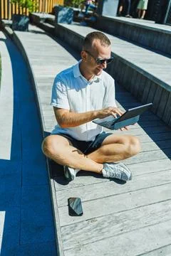 Man sitting on wooden steps using tablet in outdoor area during daytime Stock Photos