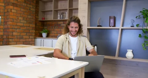 Man sitting at work table typing and laughing while reacting to laptop on-screen Stock Footage 342030994