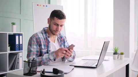 Man sitting working on laptop computer and talking on mobile phone Stock Footage 171545993