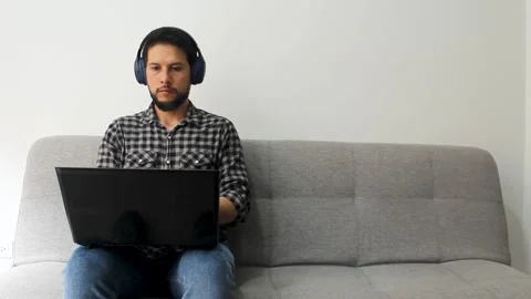 Man sitting working remotely on a black laptop over his legs Stock Footage 340583465