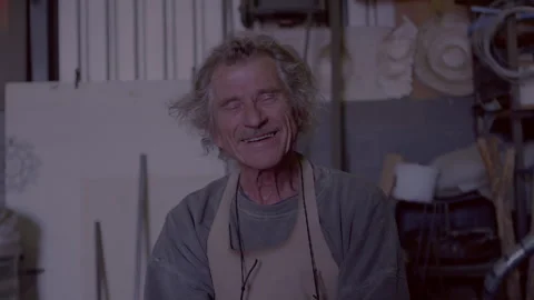 Man sitting in the workshop and smiling while looking straight at the camera Stock Footage 278994404