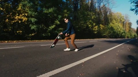 Man on a skateboard on an autumn road Video stock 81284064